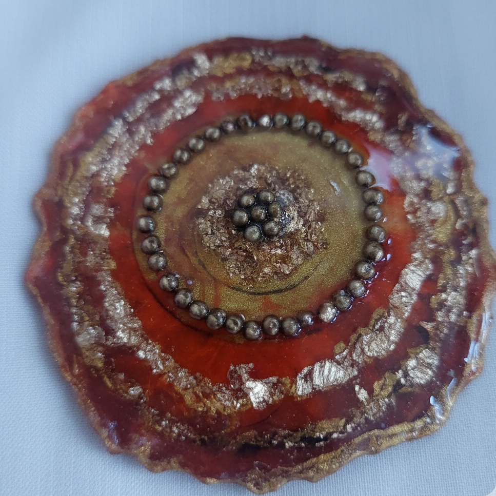 Decorative circular object with red, gold, and brown colors on a light blue background