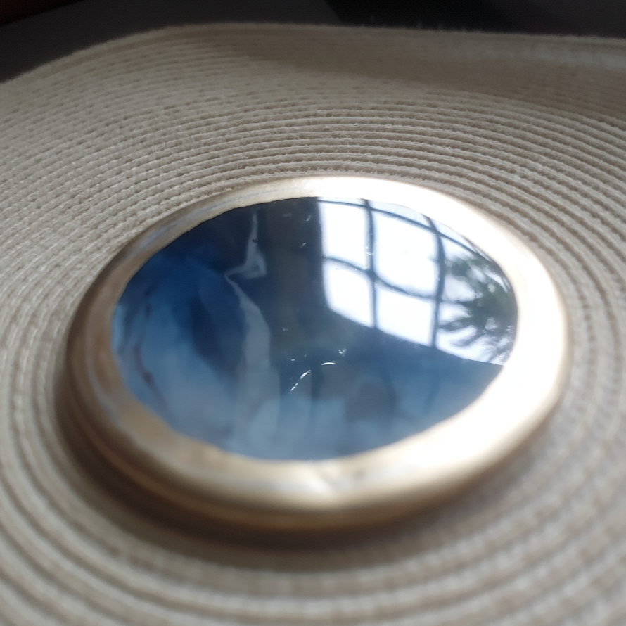Close-up of a circular object with a reflective surface on a textured beige background